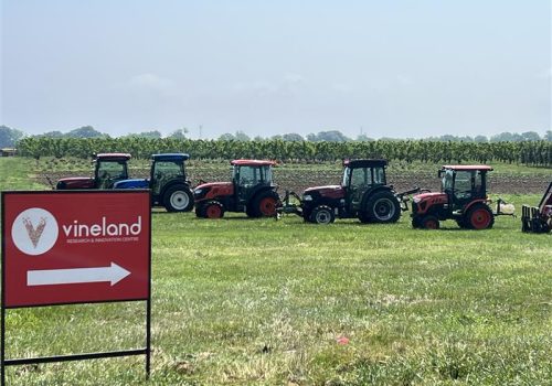 Field with a row of tractors. Vineland sign in the forefront.