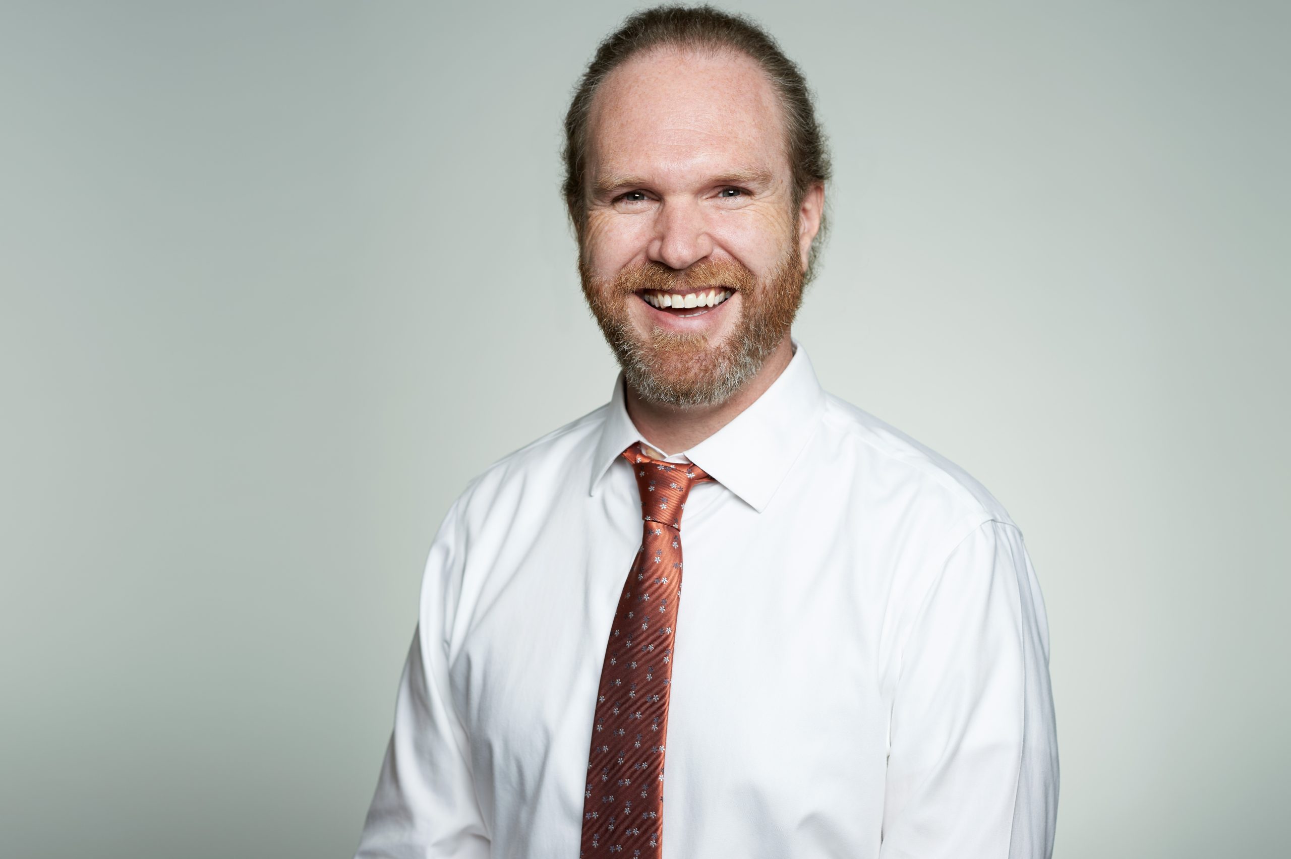 A head and shoulder shot of a smiling man with a beard.